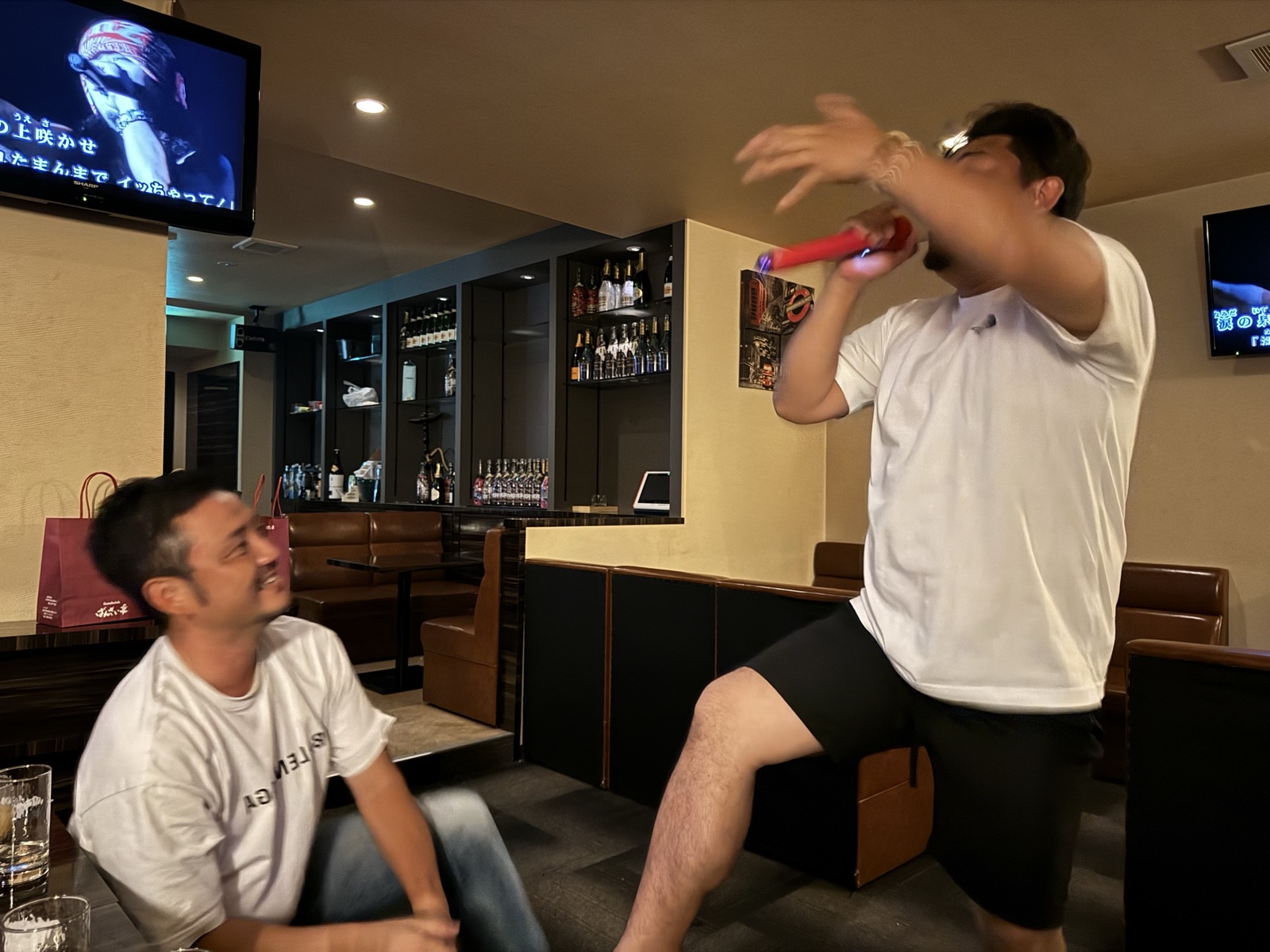 マイクを持って歌う人と笑顔で見守る人